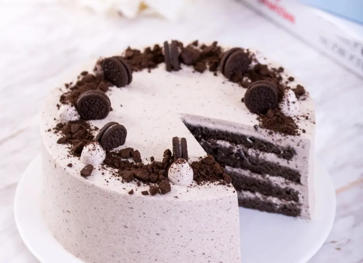 Pyszny tort z masą oreo, udekorowany pokruszonymi ciastkami i całymi ciasteczkami.