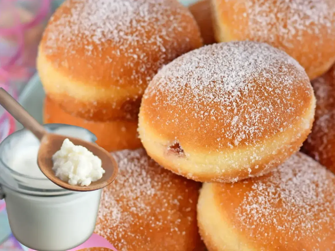 Szybkie pączki z piekarnika, oprószone cukrem pudrem, obok słoiczka z jogurtem i łyżki z jego zawartością.