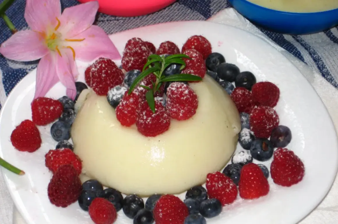 Panna cotta z malinami i borówkami, posypana cukrem pudrem. Idealny deser, który można przygotować według prostego legumina przepisu.