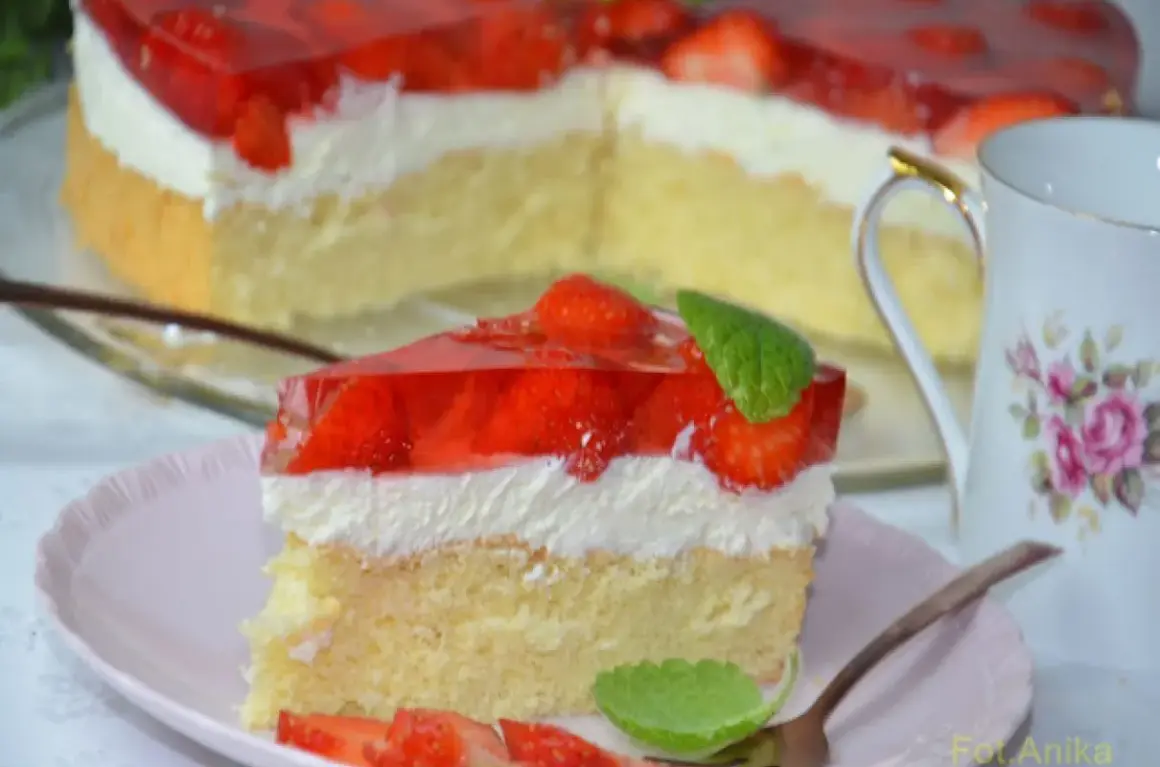 Puszysty biszkopt z truskawkami i mascarpone, oblany galaretką. Idealny deser na letnie popołudnie.