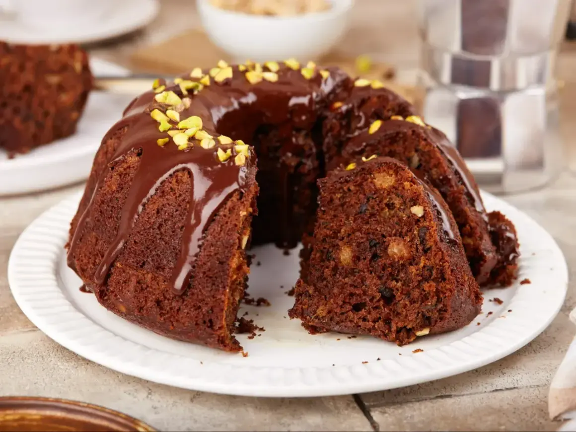 Pyszna, wilgotna babka czekoladowa z bakaliami, polana polewą i posypana pistacjami. Idealna na deser.