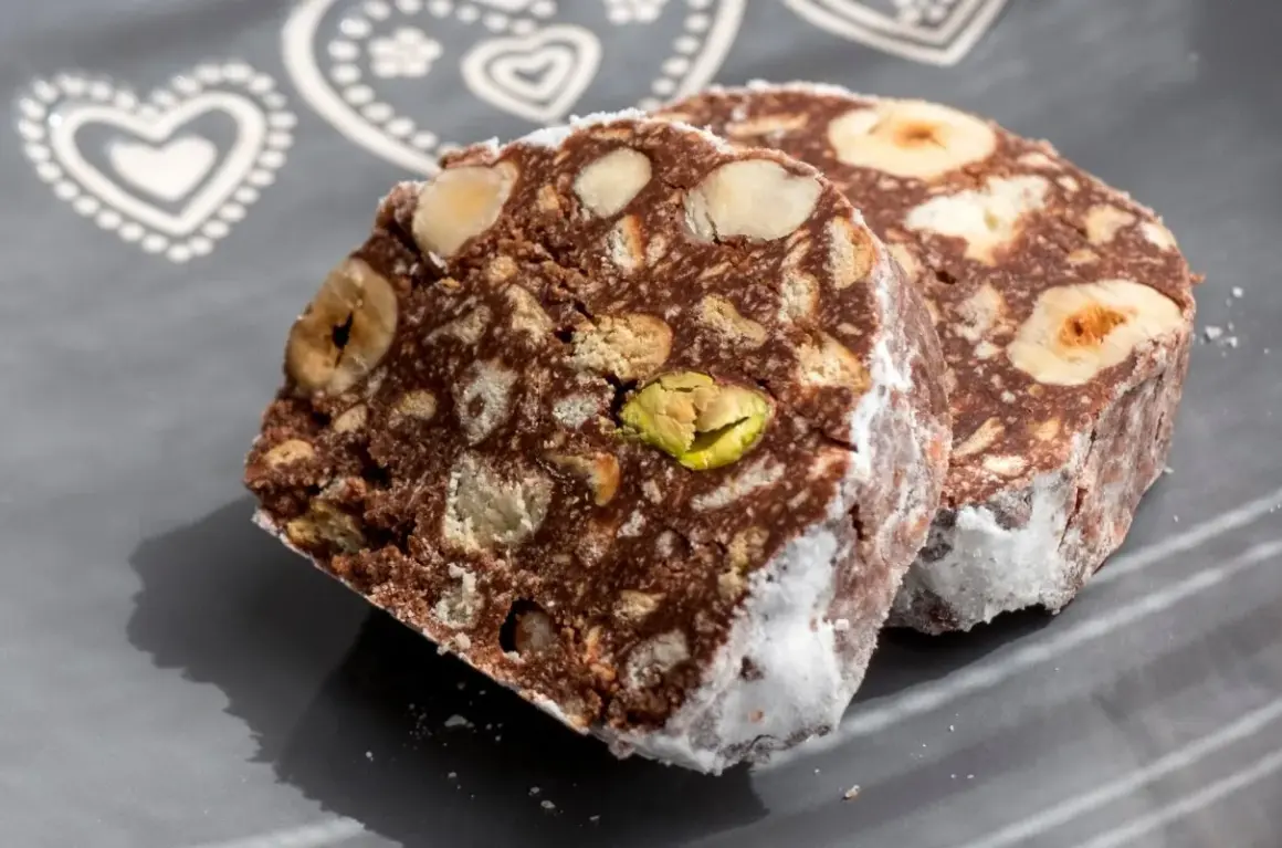 Dwa kawałki czekoladowego przysmaku z orzechami i pistacjami, przypominające blok czekoladowy przepis babci.