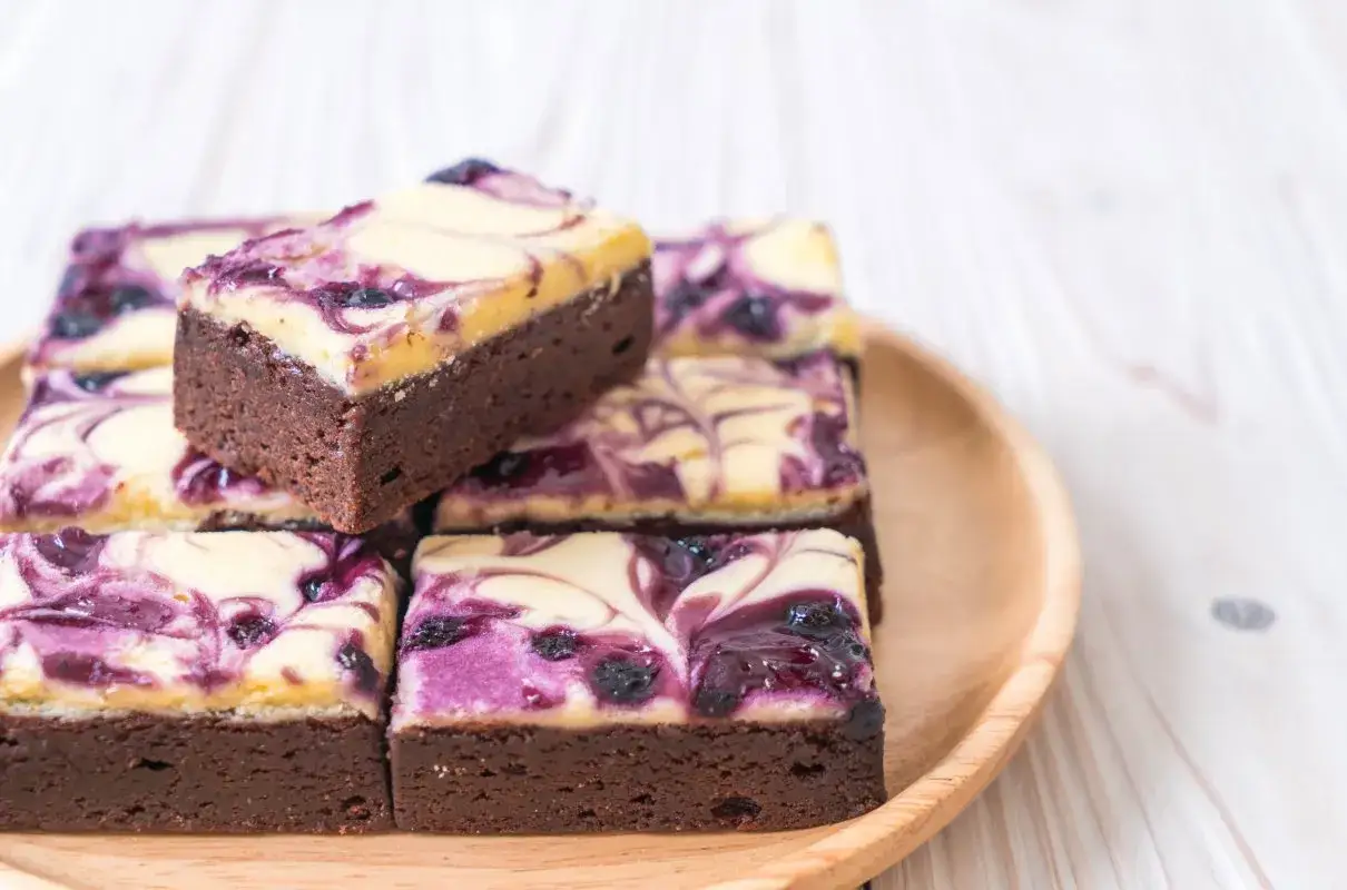Czekoladowe brownie z kremową warstwą i jagodami. Pyszne ciasto bez cukru, idealne na deser.