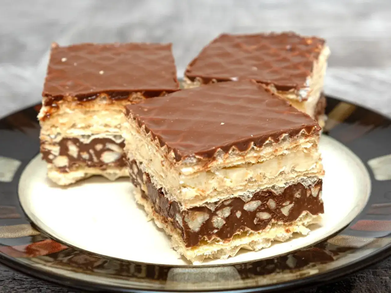 Trzy kawałki wafelka z czekoladą i orzechami. Pyszna masa do wafli kusi swoim wyglądem.