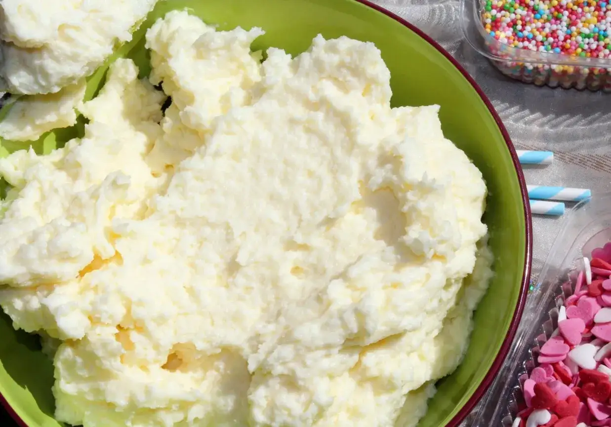 Puszysta masa budyniowa z mascarpone w zielonej misce, gotowa do dekorowania babeczek kolorową posypką.