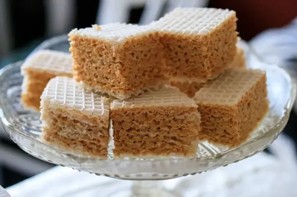 Słodkie wafle przekładane kremem z mleka w proszku, ułożone na szklanej paterze.