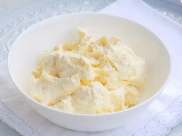 Puszysta masa budyniowa z mascarpone w białej misce, gotowa do użycia w deserach.