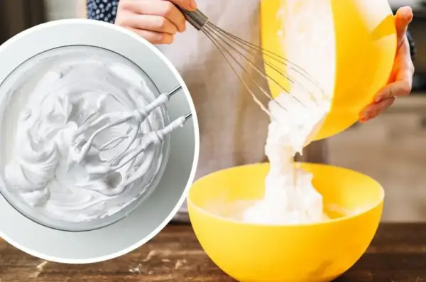 Kremowa masa z mascarpone, ubijana mikserem, przelewana z żółtej miski do drugiej.
