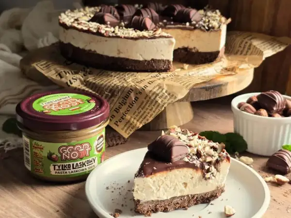 Pyszne ciasto kinder bueno z mascarpone, udekorowane czekoladą i orzechami. Obok słoik pasty z orzechów laskowych.