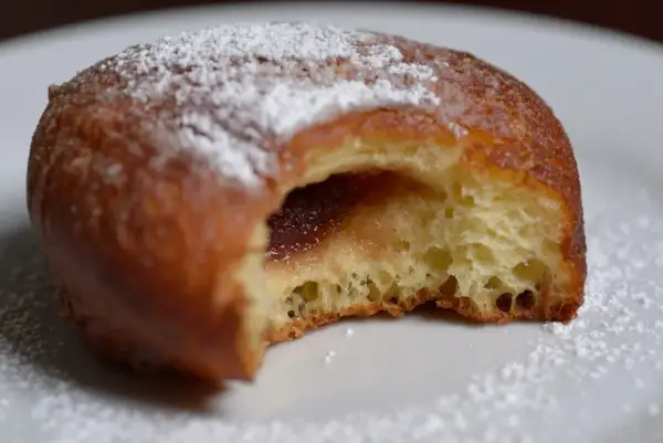 Puszysty pączek z dżemem, posypany cukrem pudrem, jak z babcinego, starego przepisu na pączki.