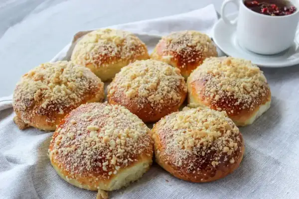 Puszyste bułki z kruszonką, idealne na prosty przepis na bułki. Obok filiżanka gorącej herbaty.