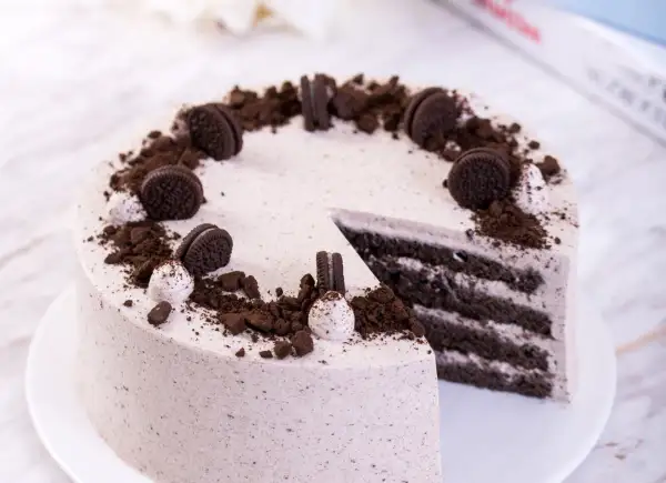 Pyszny tort z masą oreo, udekorowany pokruszonymi ciastkami i całymi ciasteczkami.
