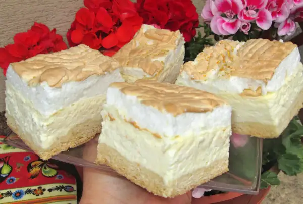 Sernik z rosą z wiaderka na dużą blachę, puszysty i pyszny, z bezą i kwiatami w tle.