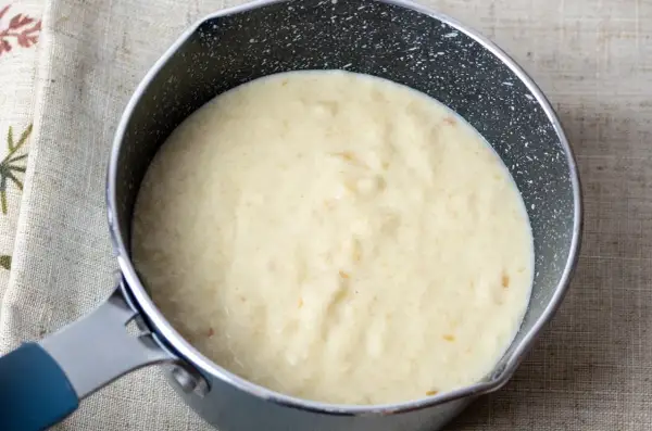 Kremowy sos z mascarpone w rondelku, gotowy do podania z deserem.