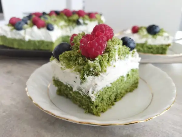 Zielone ciasto leśny mech na dużą blachę, przełożone kremem z serkiem mascarpone, ozdobione malinami i borówkami.